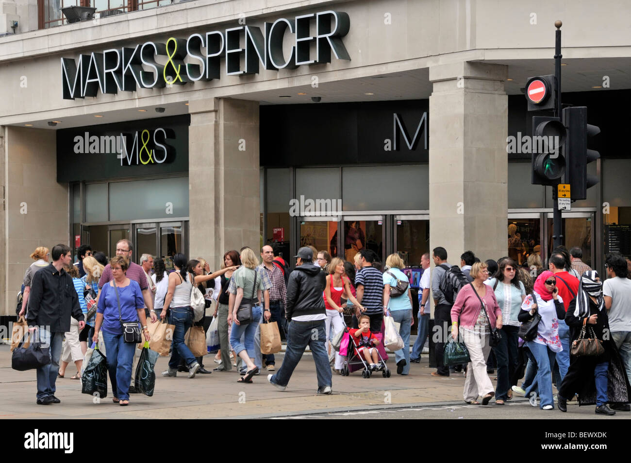 Busy Oxford Street shopping crowd of shoppers & tourist people walking on pavement Marks and Spencer Marble Arch retail business shop front London UK Stock Photo