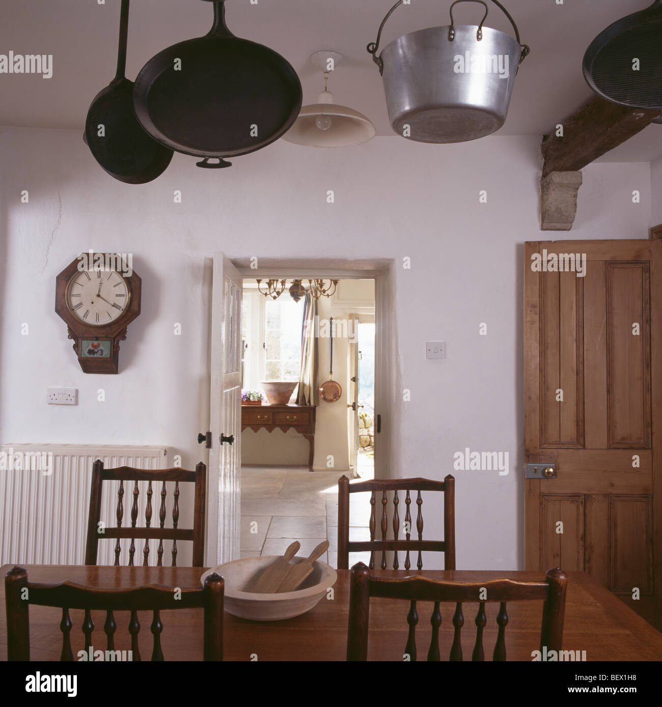Castiron and steel pans on ceiling in simple white dining room with