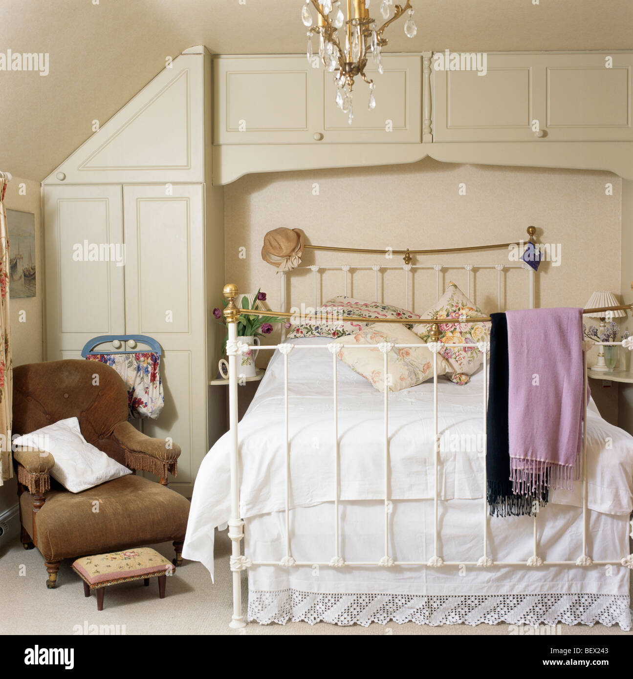 Brown velvet armchair beside brass bed with white bedlinen in country