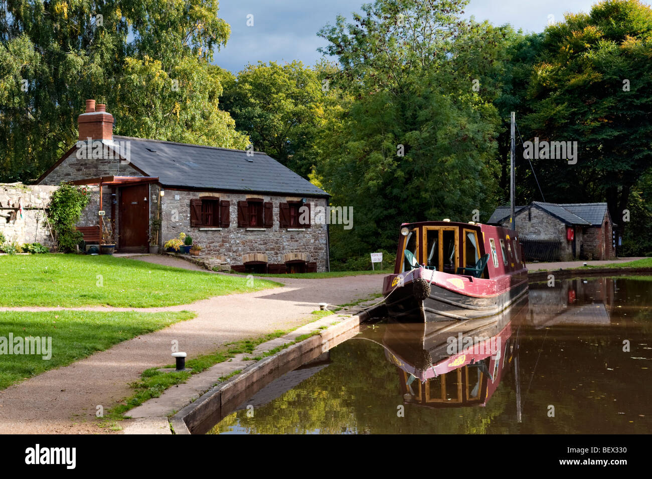 Picturesque reflection of boat house and moored canal boat on the Monmouth and Brecon Canal taken at Llangynidr mid Wales Stock Photo