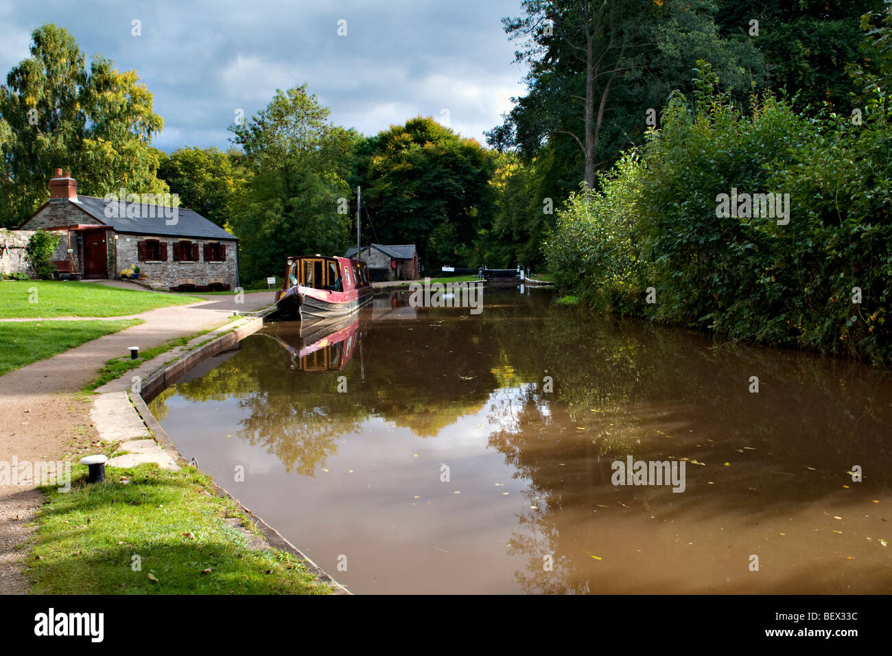 Picturesque reflection of boat house and moored canal boat on the Monmouth and Brecon Canal taken at Llangynidr mid Wales Stock Photo