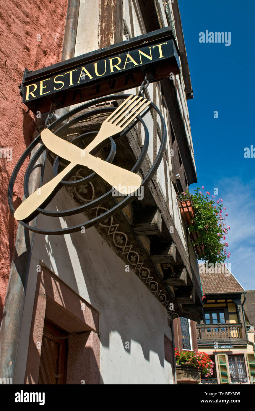 ALSACE French Restaurant sign of crossed knife and fork with typical sunny floral Alsace houses in background France Stock Photo