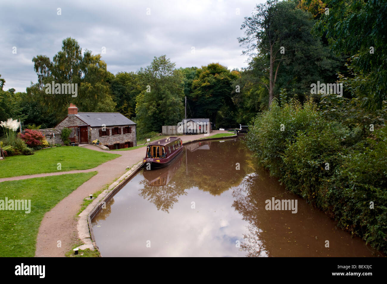 Picturesque reflection of boat house and moored canal boat on the Monmouth and Brecon Canal taken at Llangynidr mid Wales Stock Photo