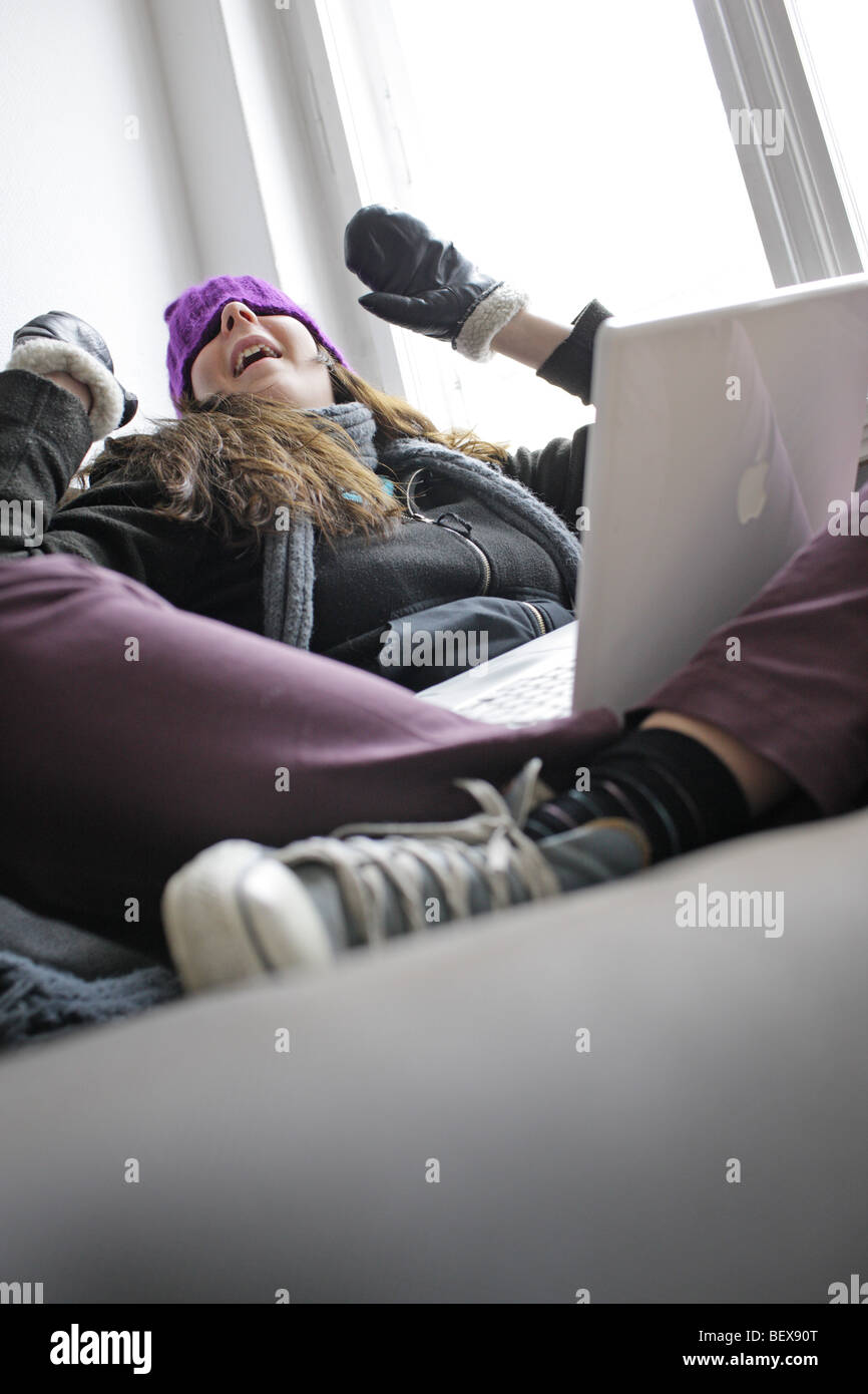 Saving heating coasts, young woman at home wearing a cap and gloves . Stock Photo