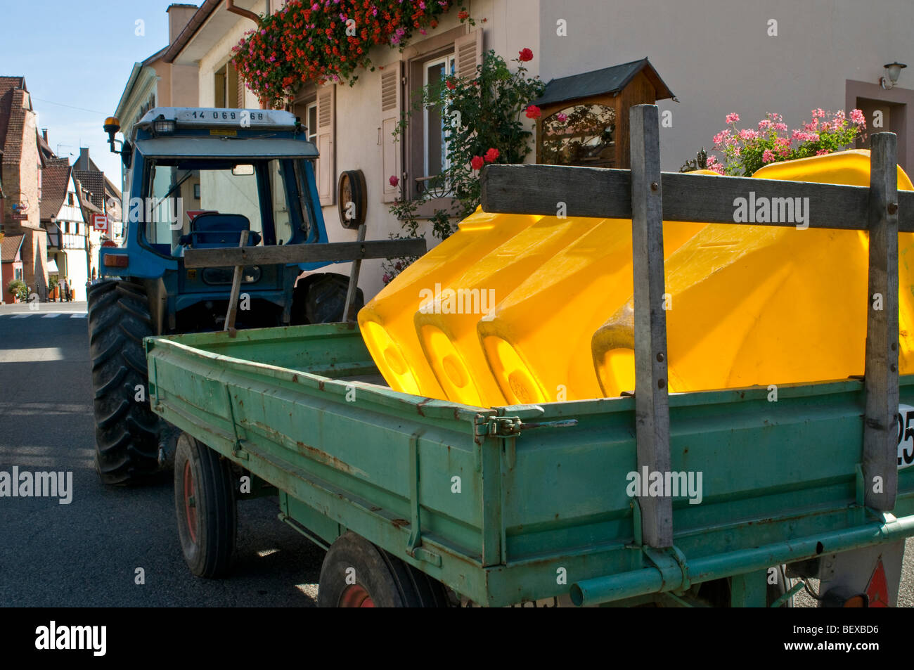 HARVEST TRACTOR ALSACE Empty yellow grape harvest tubs with tractor and trailer at harvest days end outside Eguisheim winery Alsace France Stock Photo