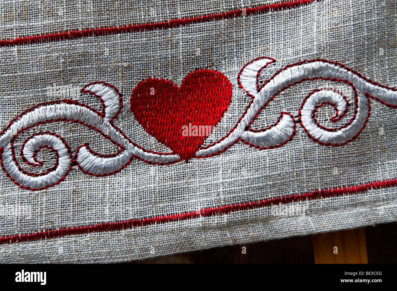 HEART LOVE EMBROIDERY FABRIC TEXTURE Close view on red heart embroidered on border of linen table cloth Stock Photo