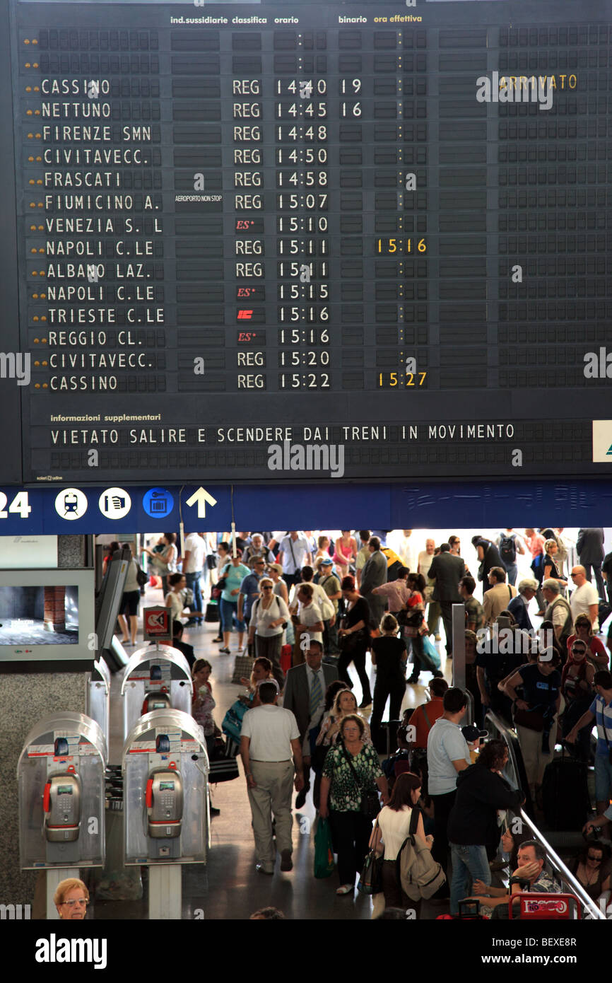 Crowds pass by a board showing departure times at Stazione Termini in Rome Stock Photo