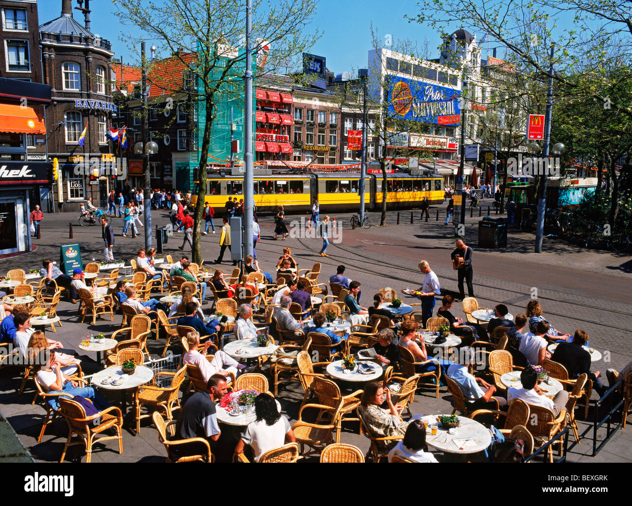 Summertime tourists, trams, and street musicians at outdoor sidewalk