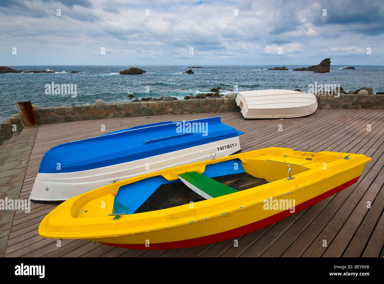 Three rowing boats, of which two upside down, pulled ashore in Roque de las Bodegas on Tenerife, Canary Islands Stock Photo
