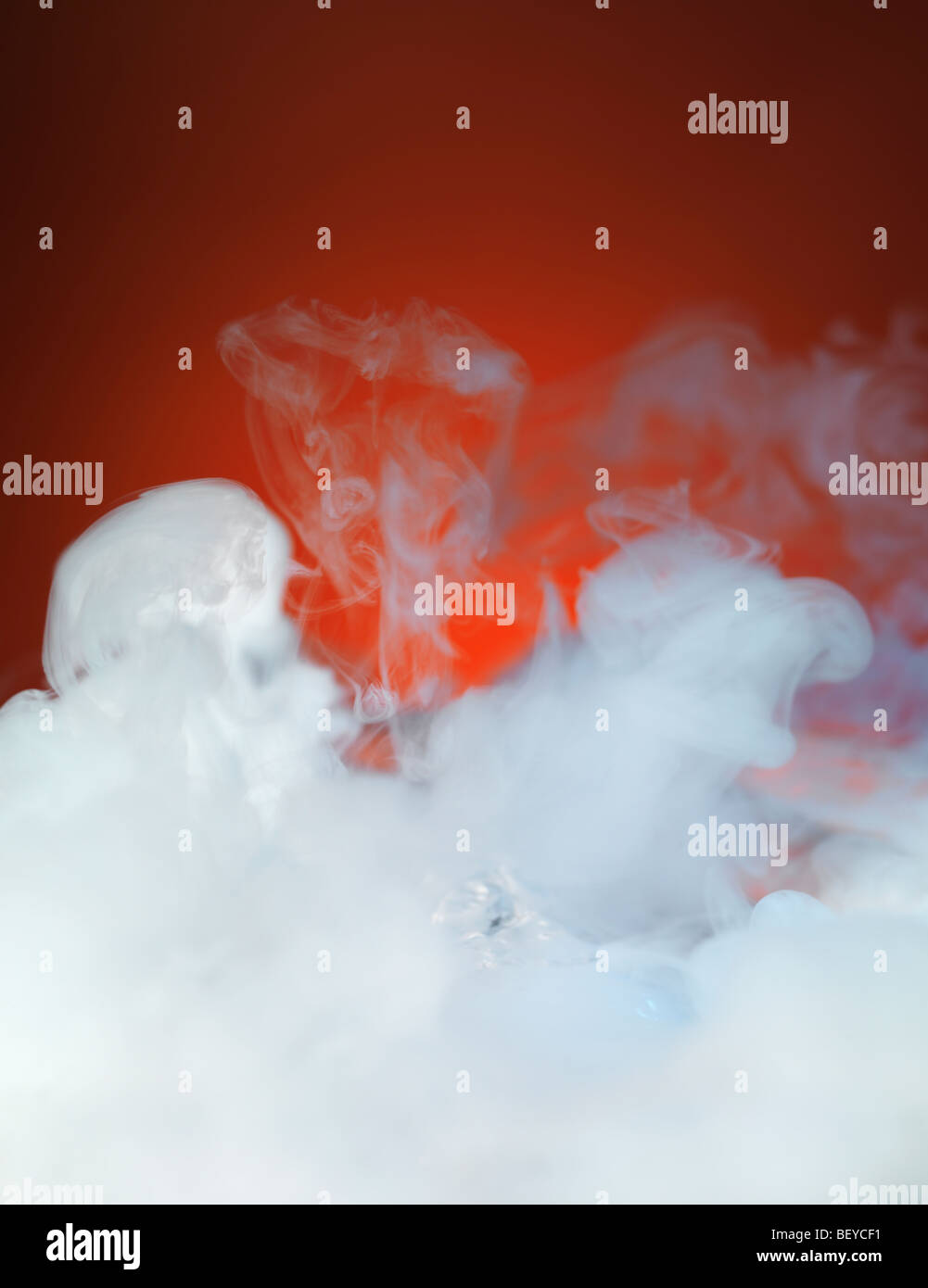 Dense white smoke on red background Stock Photo