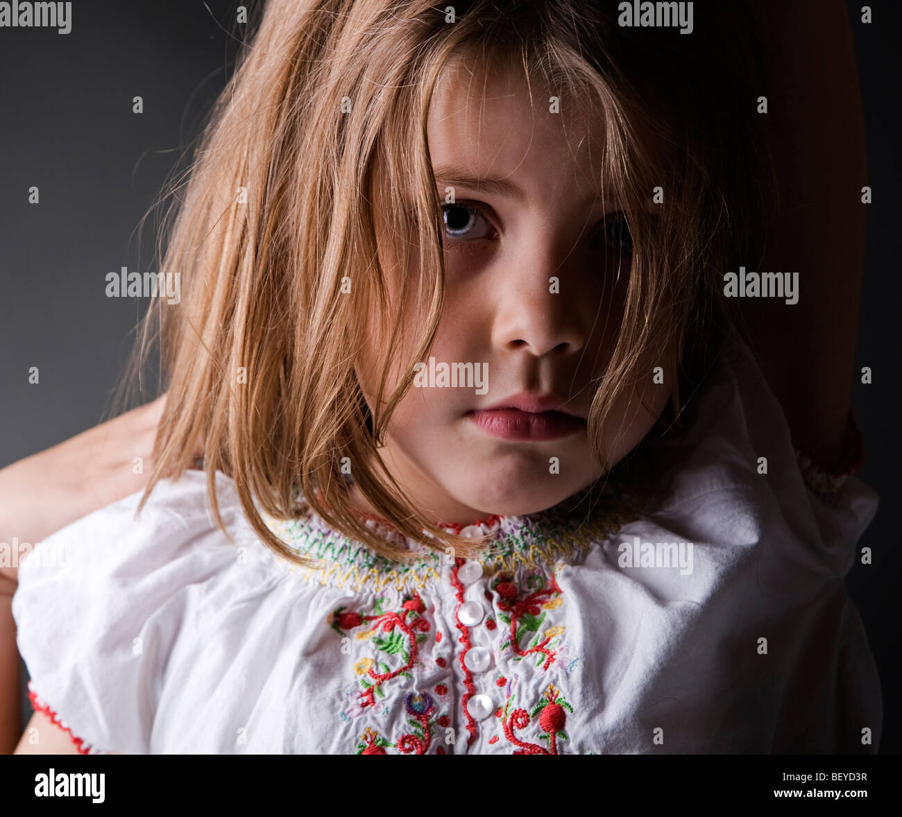 An adorable little girl in a vulnerable pose looking concerned Stock Photo