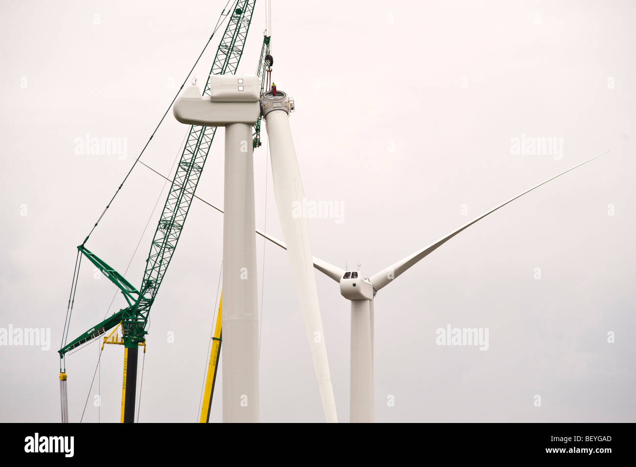 Blades being lifted by cranes for fitting on Nordex N90 wind turbine under construction at