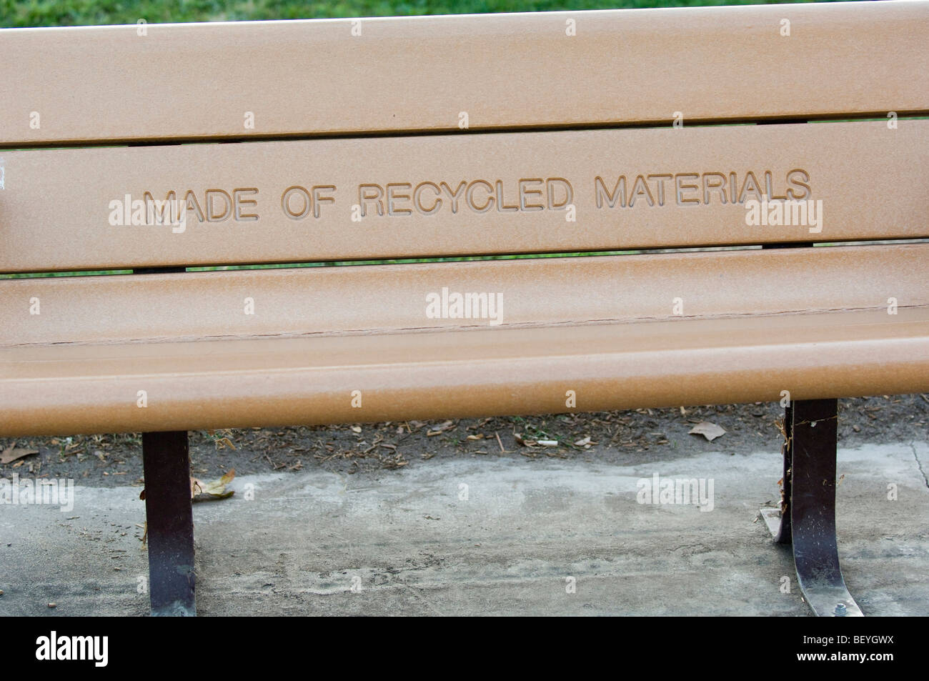 Park bench with a prominently displayed message indicating that it is manufactured with recycled materials. Stock Photo
