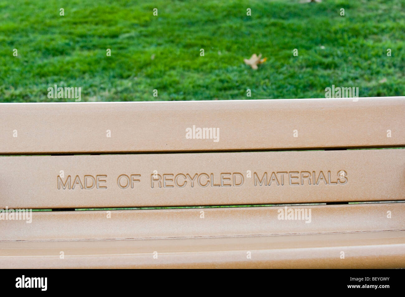 Park bench with a prominently displayed message indicating that it is manufactured with recycled materials. Stock Photo