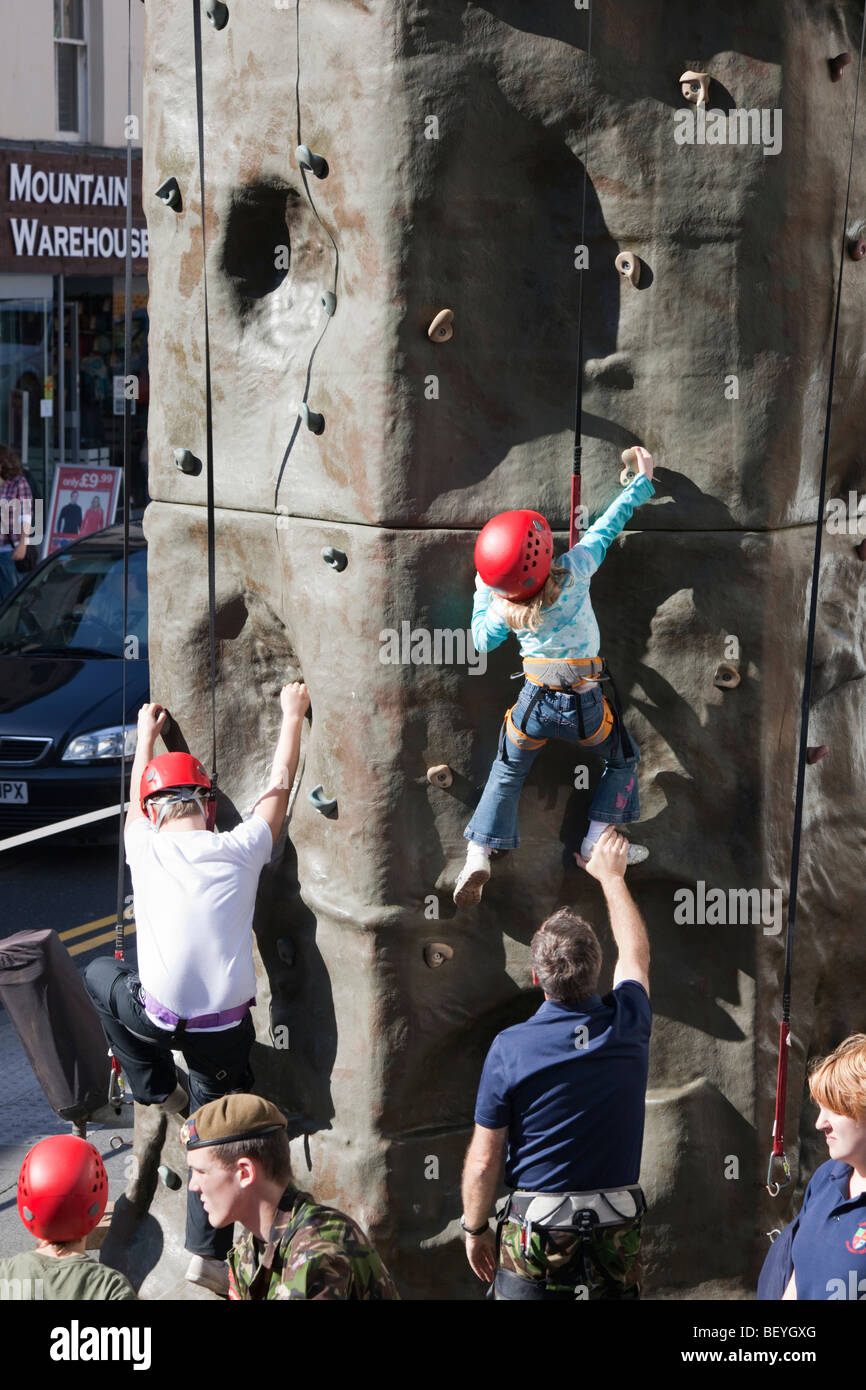 Children learning to rock climb on outdoor artificial climbing wall in an Army Help for Heros fund raising event. England UK Stock Photo