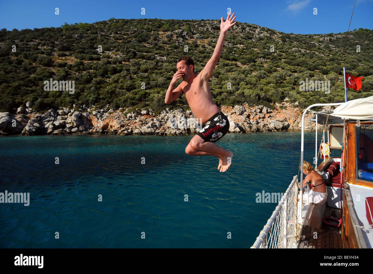 A male tourist jumps off a boat straight into the Aegean sea during a pleasure cruise round Kalkan Stock Photo