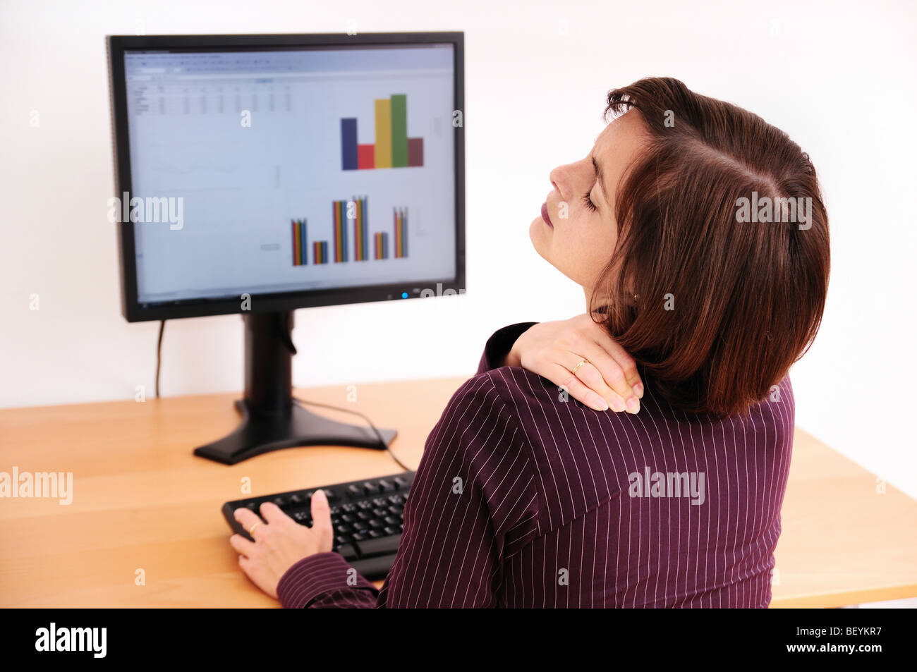 Business woman with neck pain. Focus on hand on neck with blurred