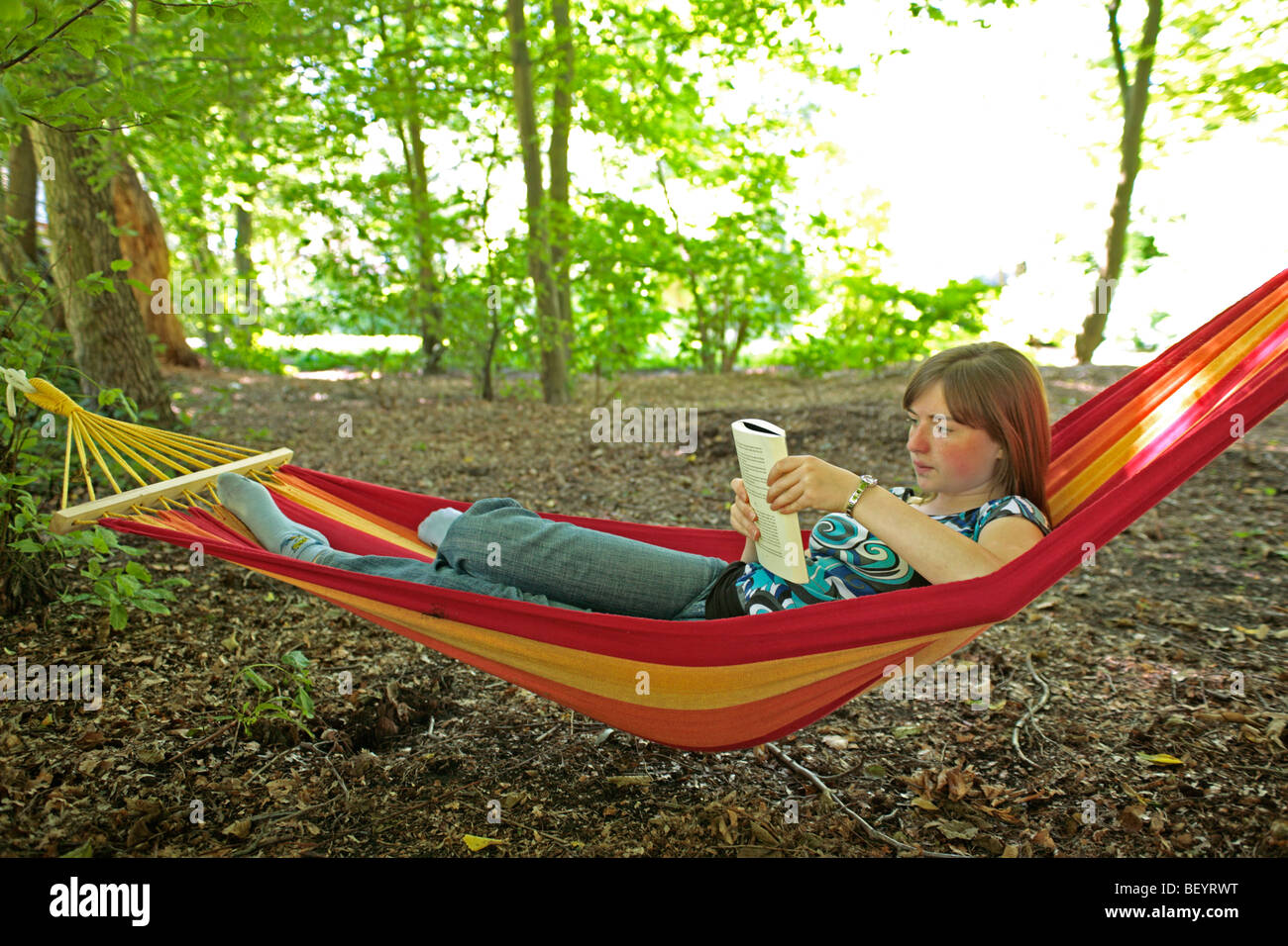 portrait of a teenage girl lying in a hammock reading a book Stock ...