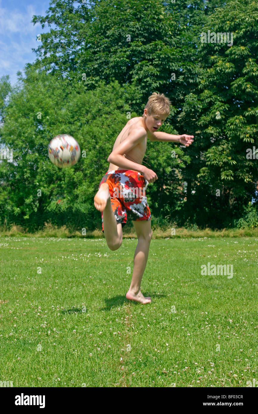 teenage boy playing football in his swimming trunks Stock Photo Alamy