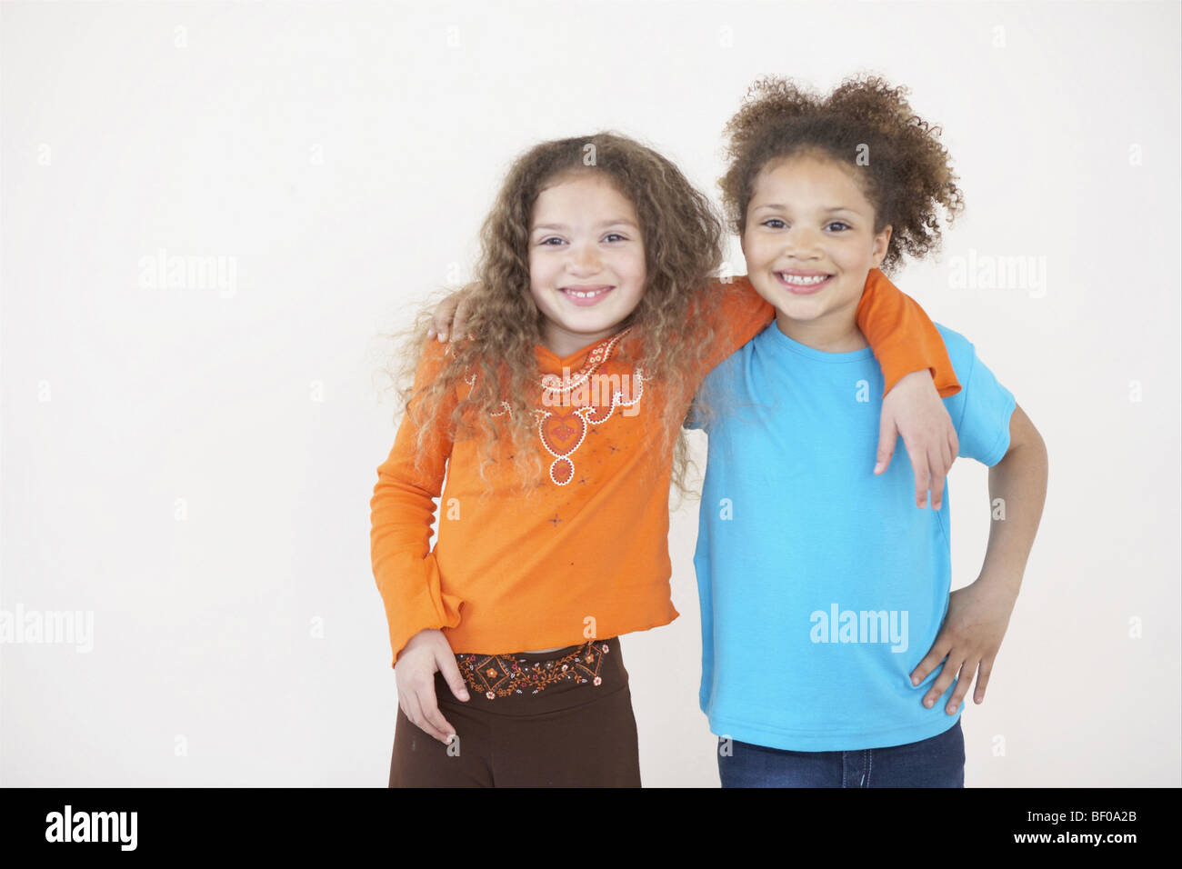 Portrait of two girls smiling with their arms around each other Stock Photo