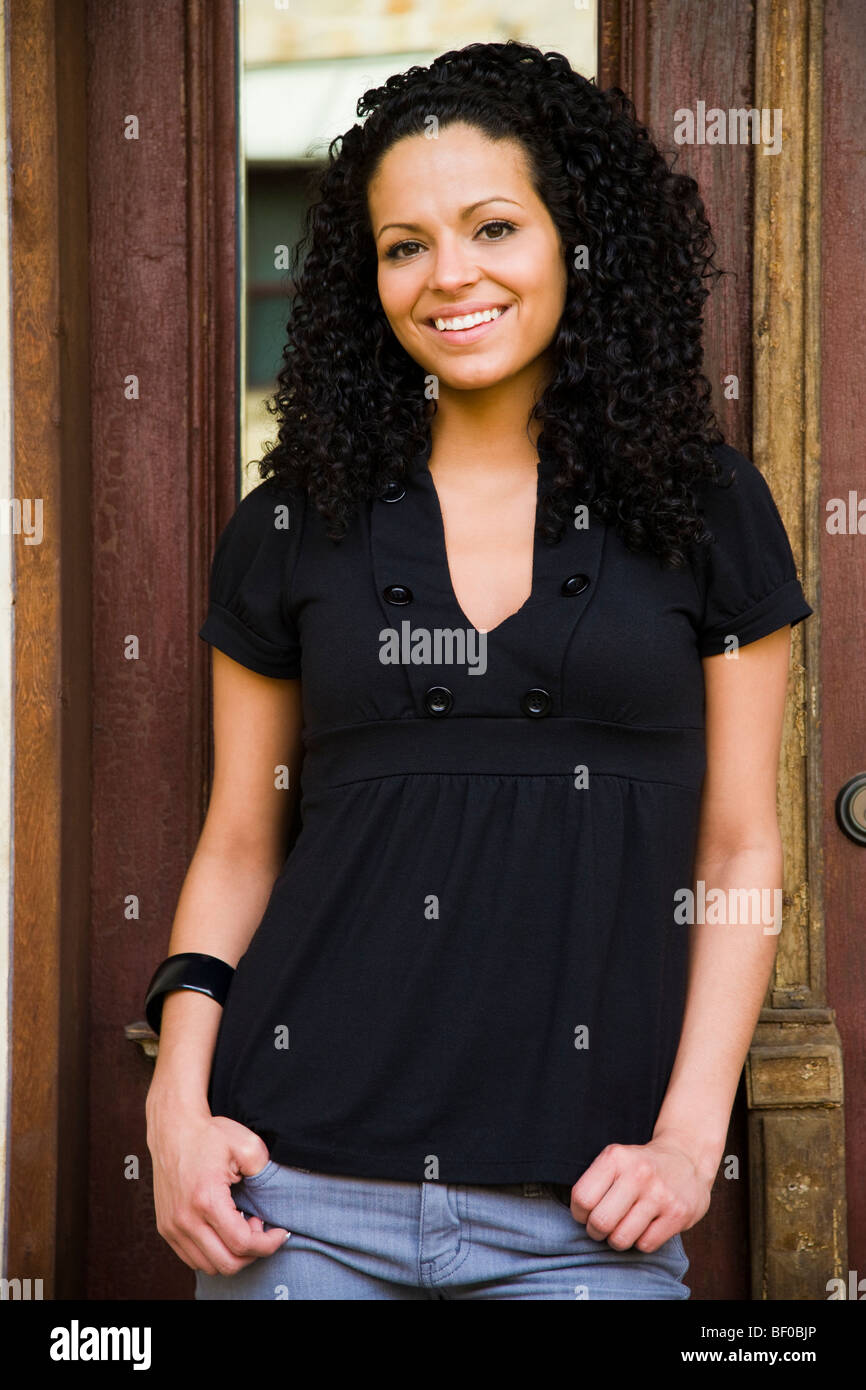Woman standing in front of a door and smiling Stock Photo - Alamy