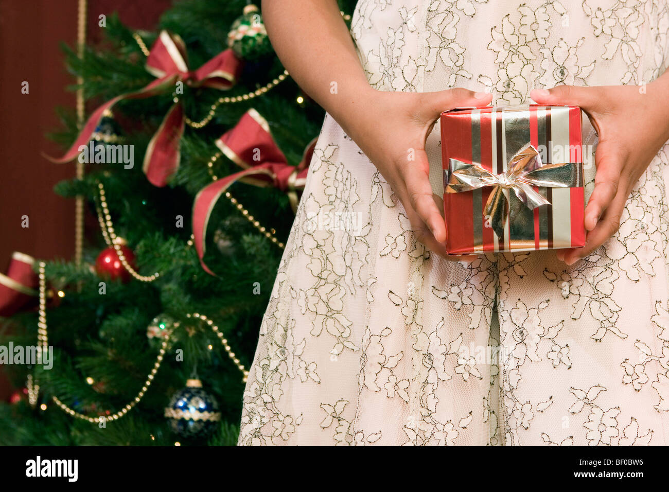 Girl in front of a Christmas tree holding a Christmas present Stock ...