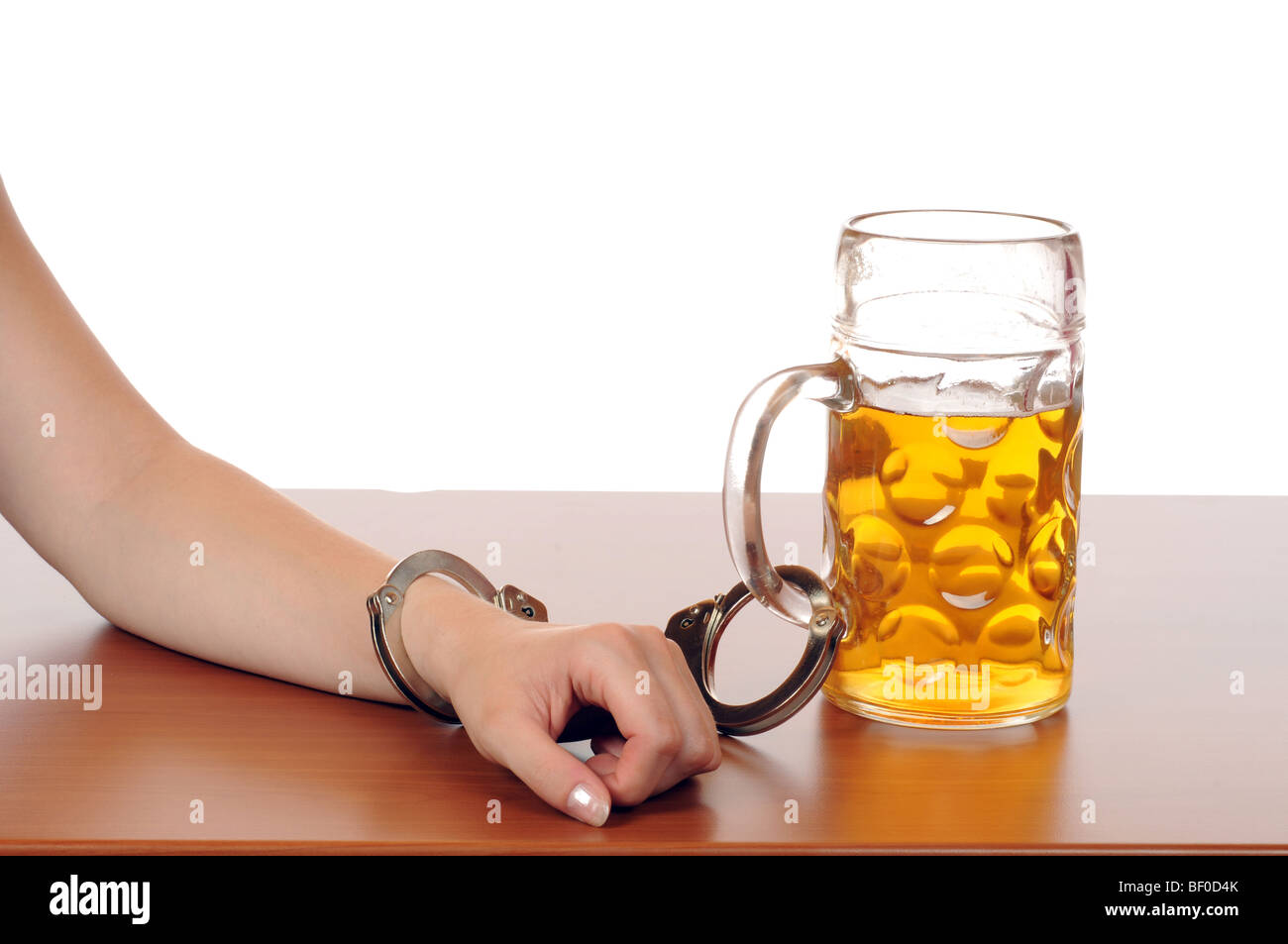 Glass of beer with handcuffs as symbol for alcohol abuse Stock Photo