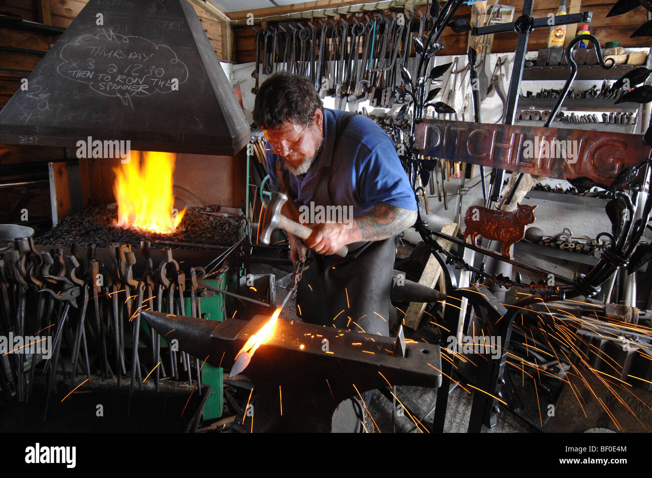 A village blacksmith forging a new sign for Ditchling in Sussex Stock Photo