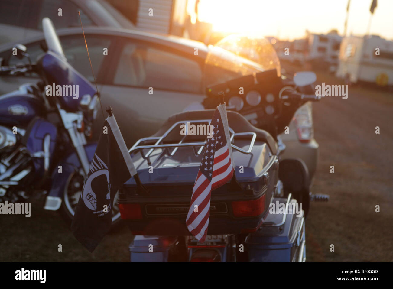 The American flag and the POW MIA flag fly on a parked motorcycle at sunset. Vietnam Veterans gather in Kokomo, Indiana Stock Photo