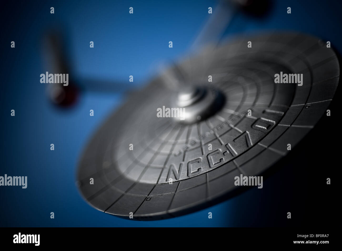 A pewter model of the famous Starship, USS Enterprise, from TV's Star Trek, displayed on a blue background. Stock Photo