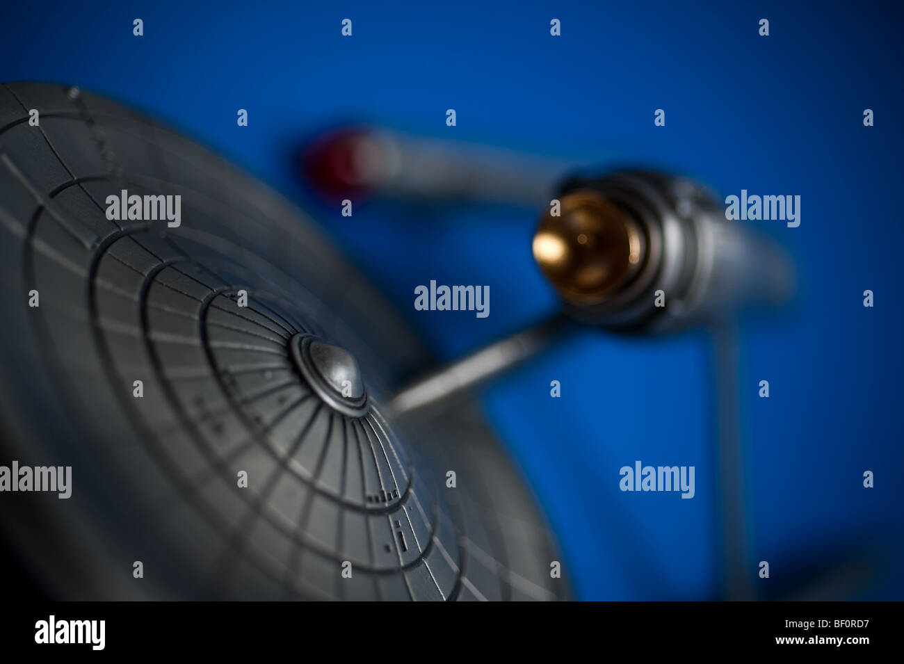 A pewter model of the famous Starship, USS Enterprise, from TV's Star Trek, displayed on a blue background. Stock Photo