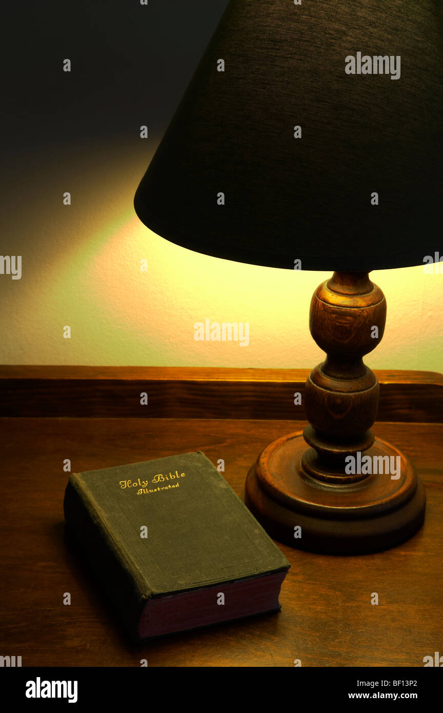 Bible lit by table lamp Stock Photo