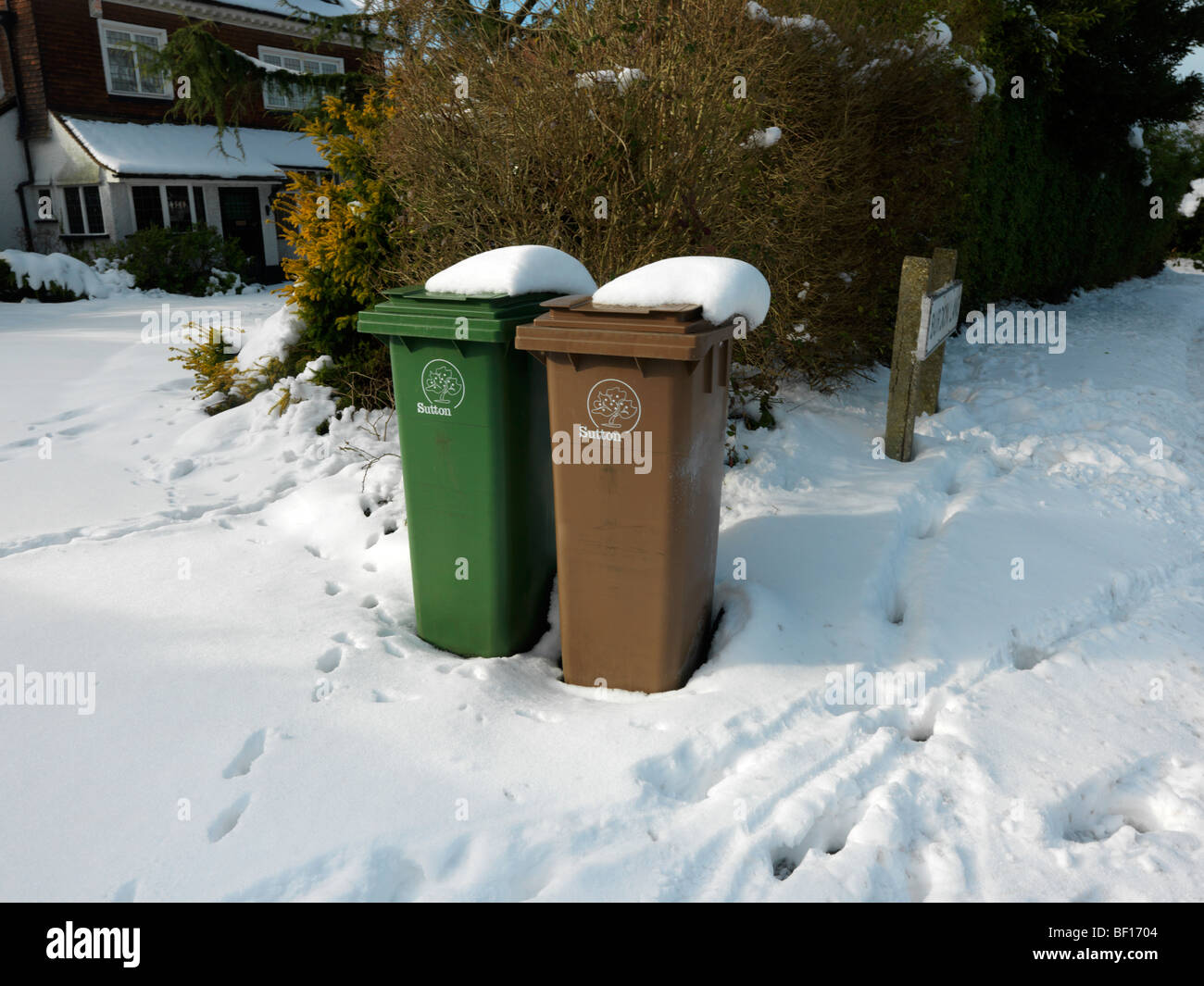Green & Brown Wheelie Bins in snow outside House awaiting collection