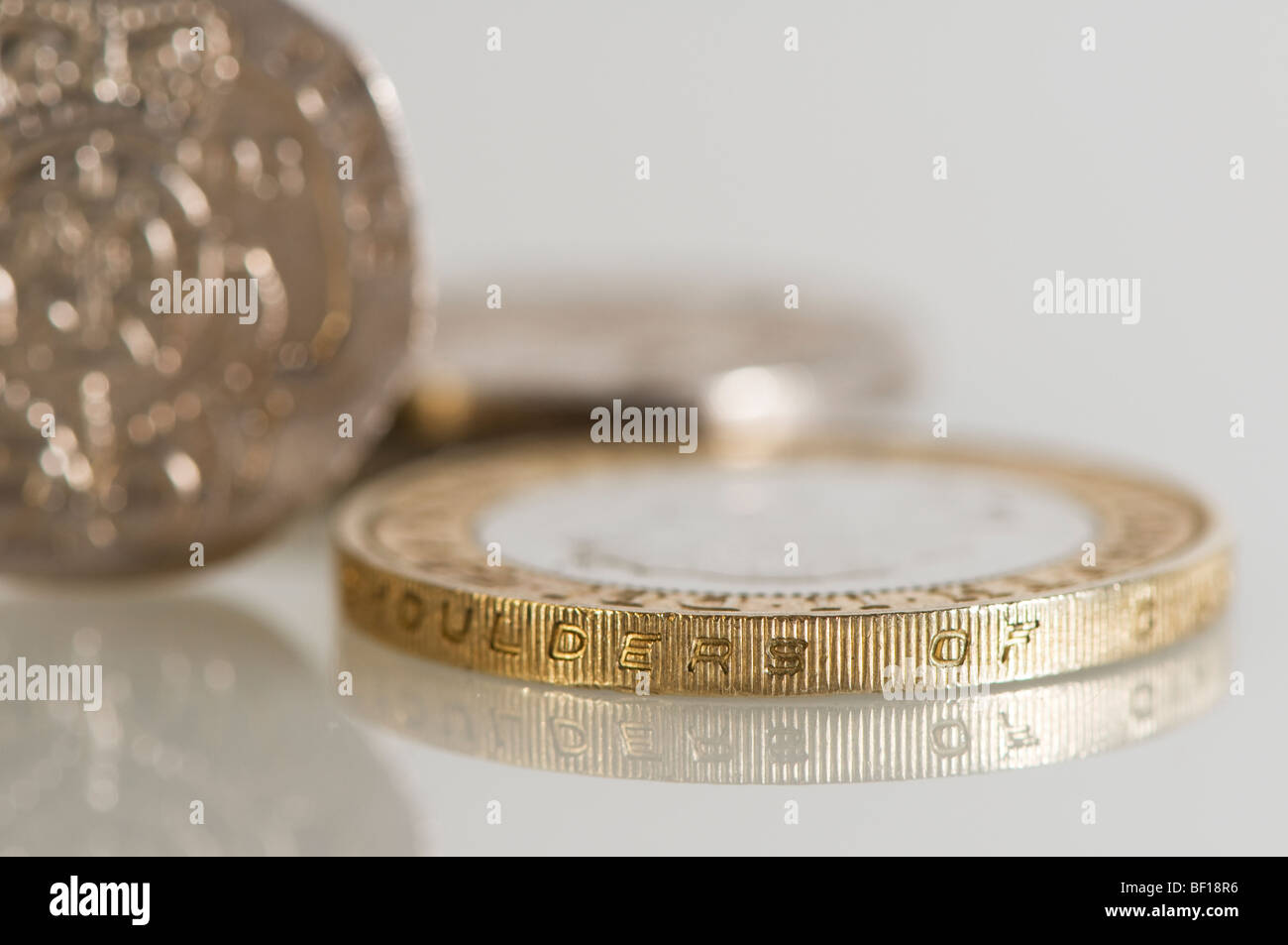 Close up shot of UK currency coins, £2 and 20p coins, shot against white with reflection. Stock Photo