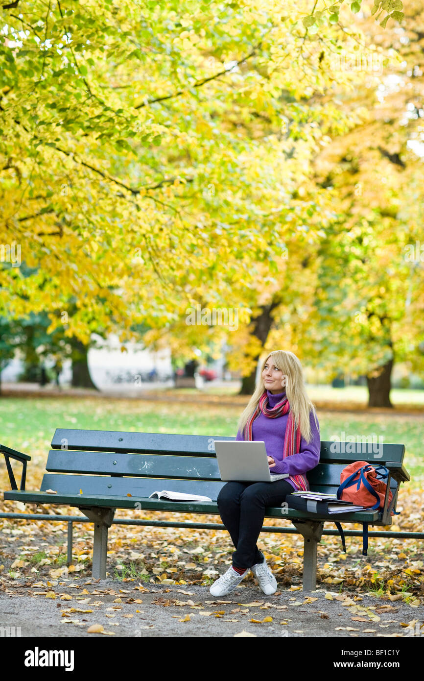 A woman sitting on bench in a park using a laptop, Stockholm, Sweden. Stock Photo