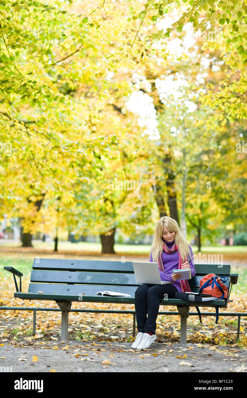A woman sitting on bench in a park using a laptop, Stockholm, Sweden. Stock Photo