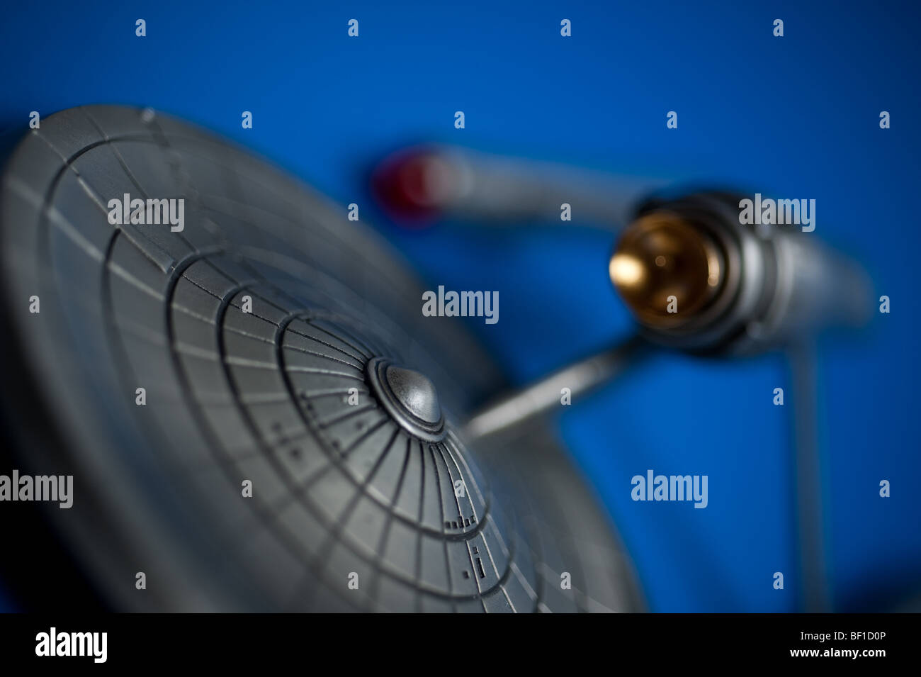 A pewter model of the famous Starship, USS Enterprise, from TV's Star Trek, displayed on a blue background. Stock Photo