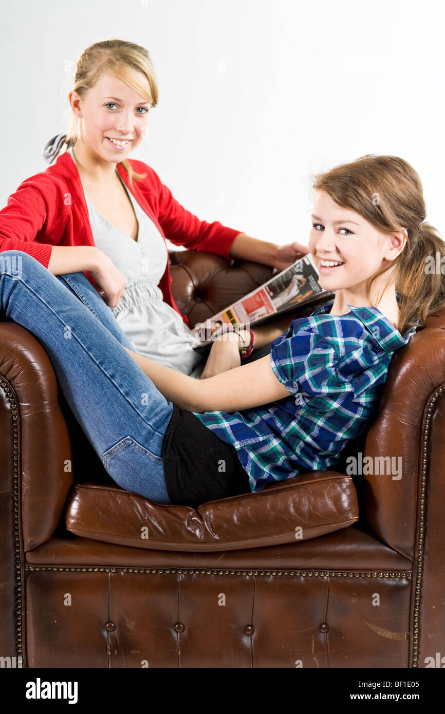 Teenage girls relaxing in an armchair. Stock Photo