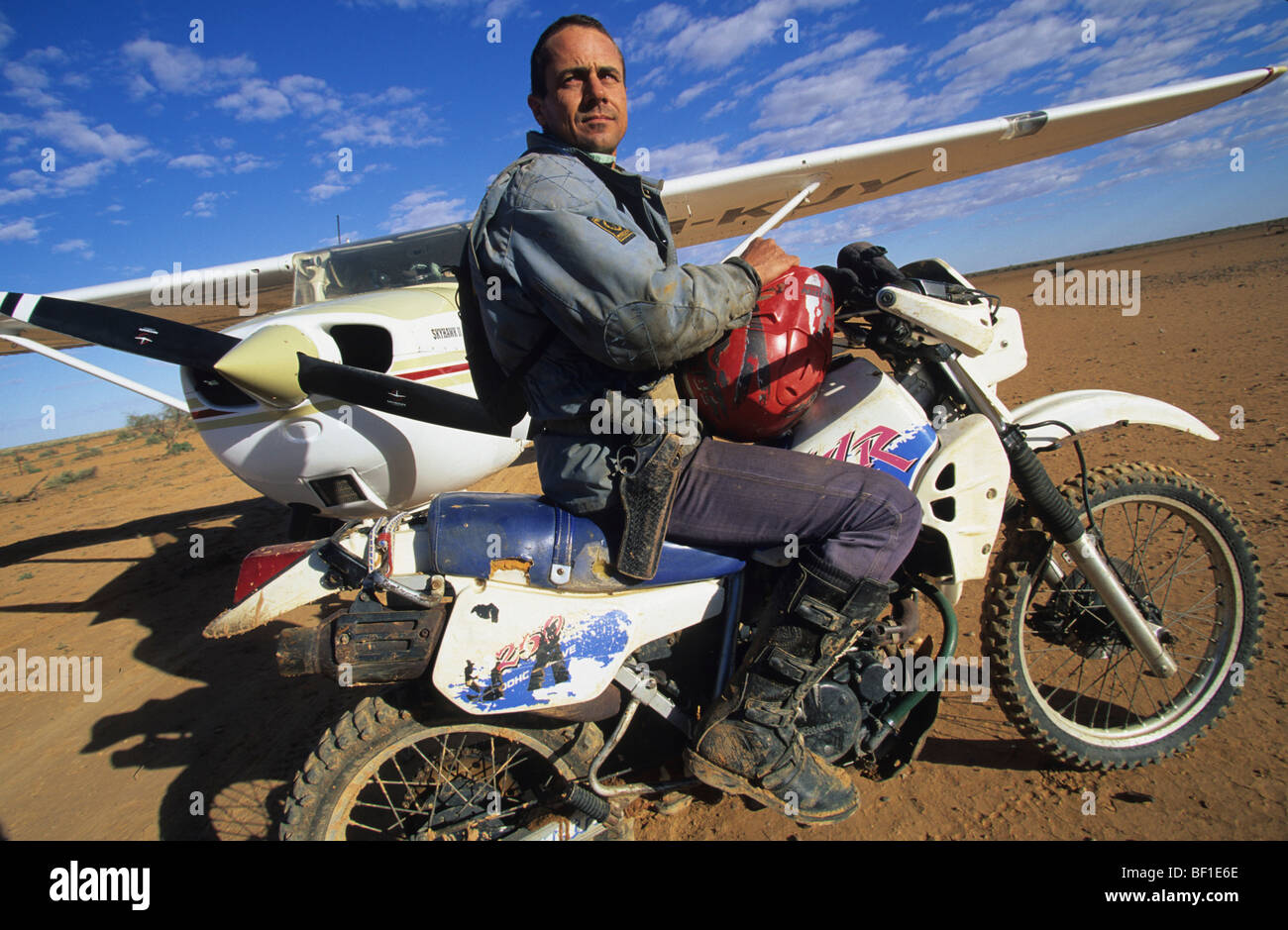 Cowboy with gun, sitting on motorbike with light airplane, Queensland Australia Stock Photo