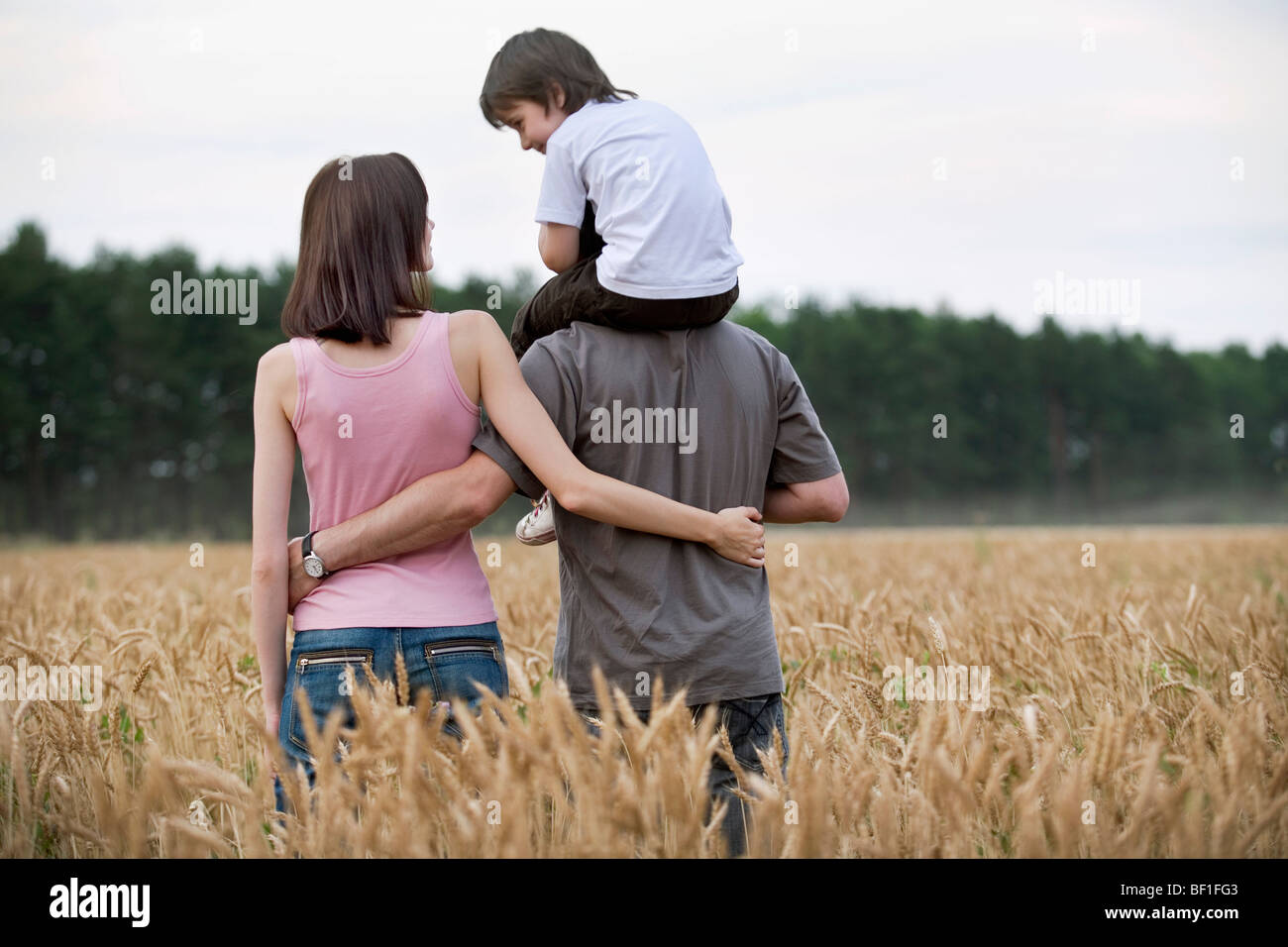 A young family walking through a wheat field Stock Photo