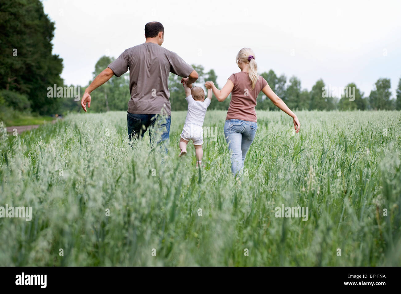A family walking through a field Stock Photo