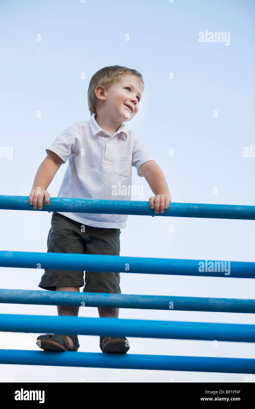 A boy standing at the top of a jungle gym Stock Photo