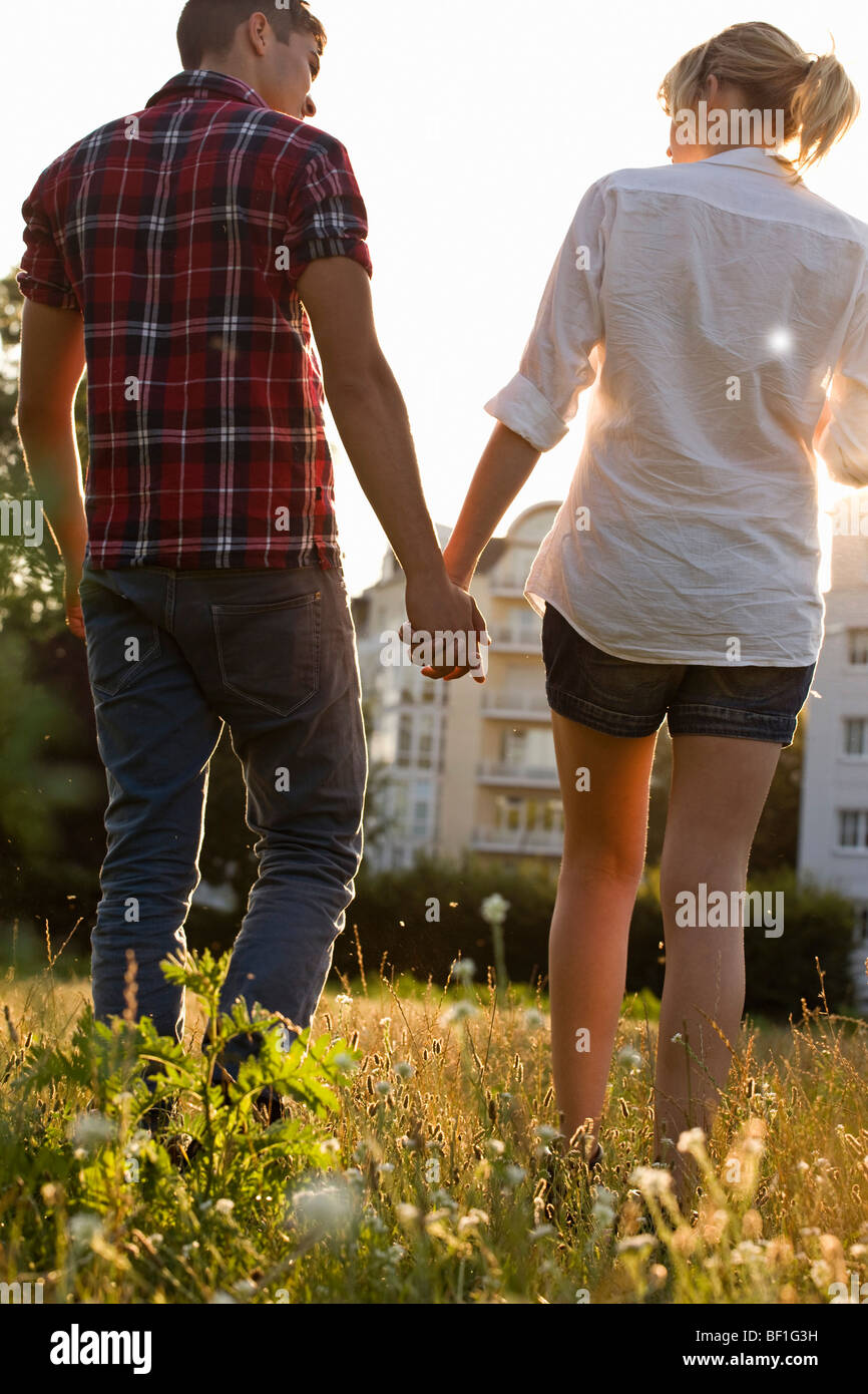 A young couple holding hands walking through a park, rear view Stock ...