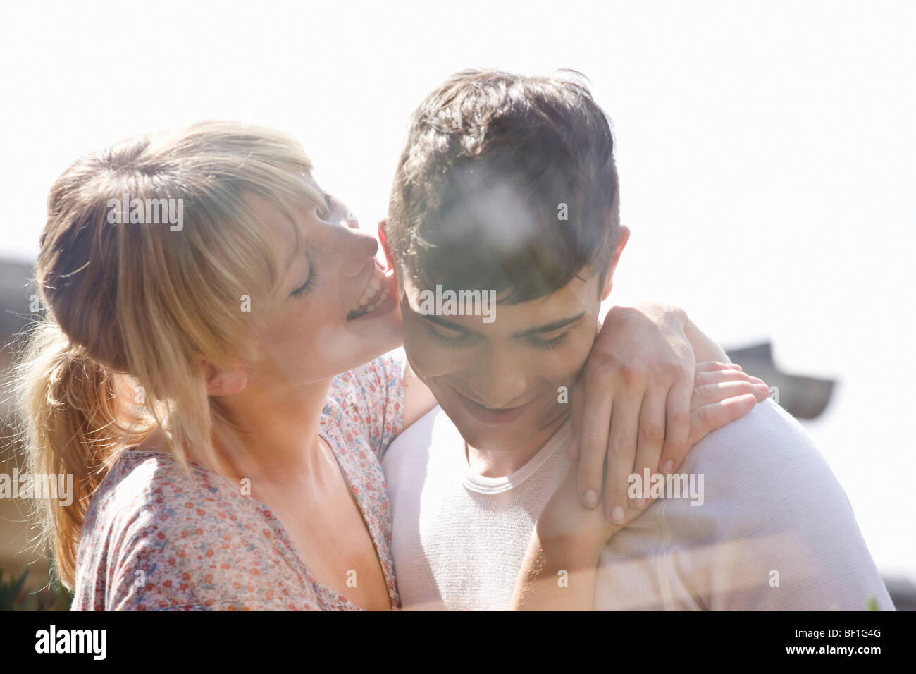 A young woman playfully licking a young man's ear Stock Photo