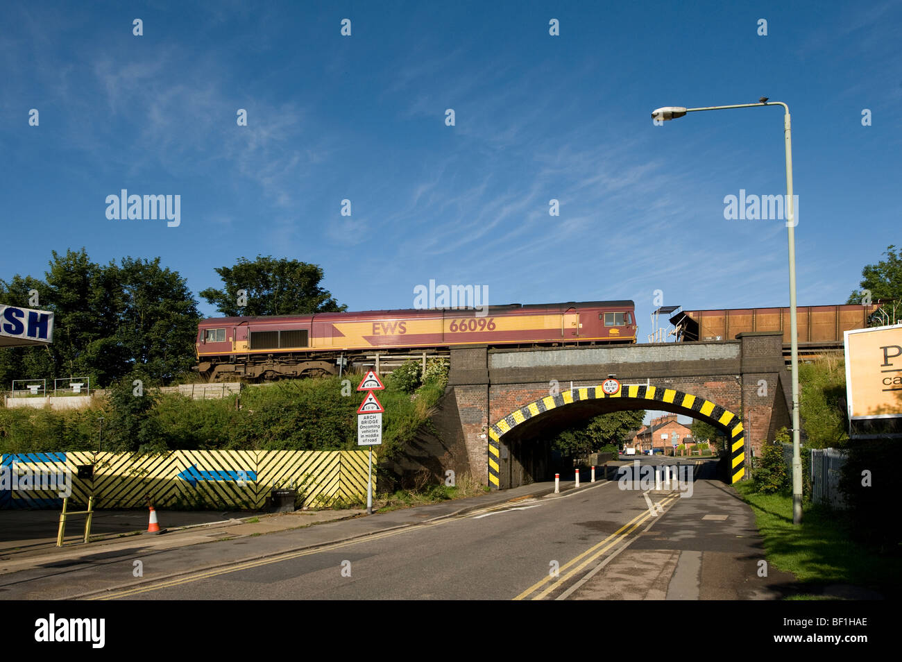 Freight train travelling over a railway bridge crossing a road in the Midlands, England Stock Photo