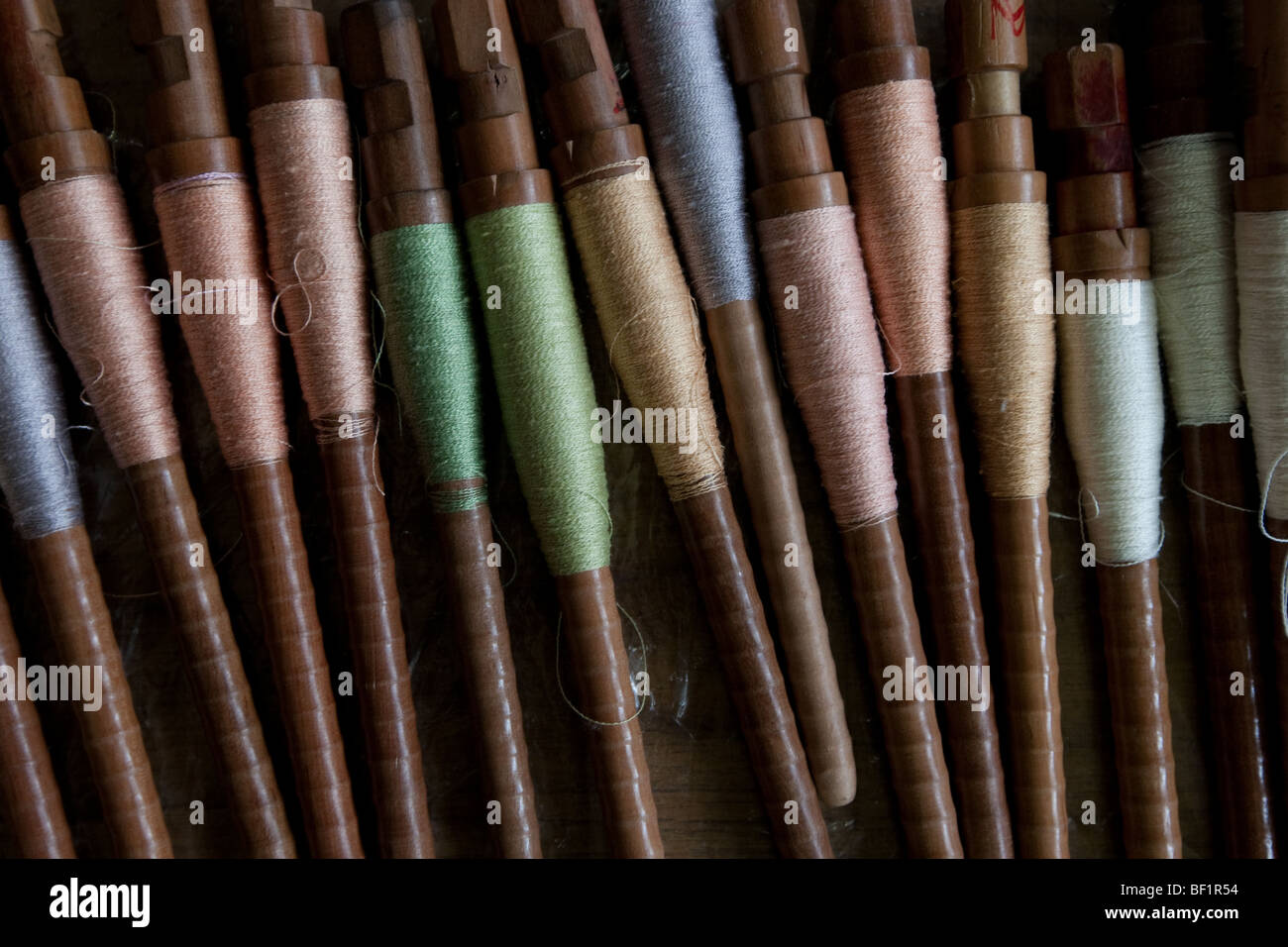 Bobbins spindles of colourful silk threads. Stock Photo