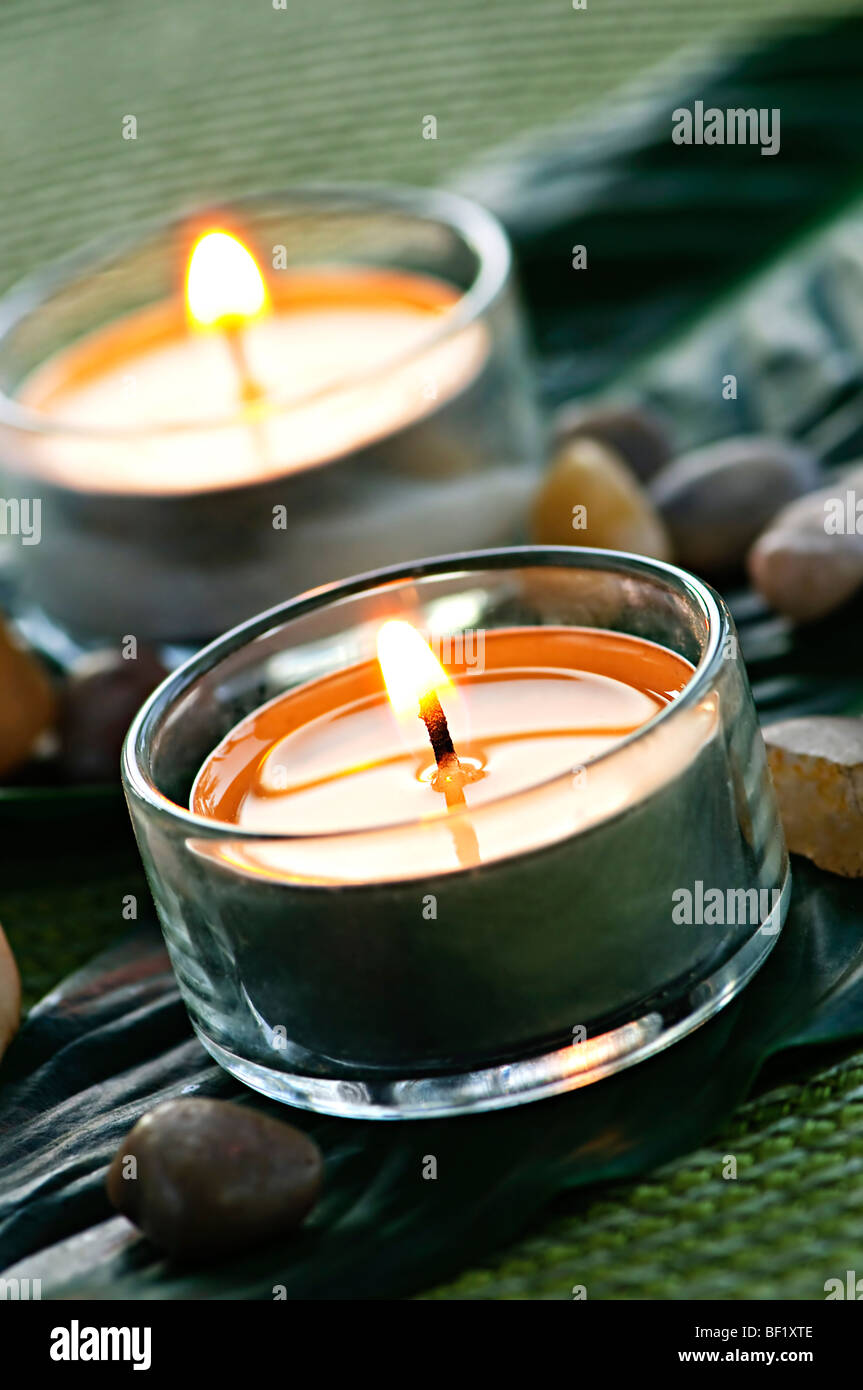 Burning candles in glass holders on green leaf Stock Photo