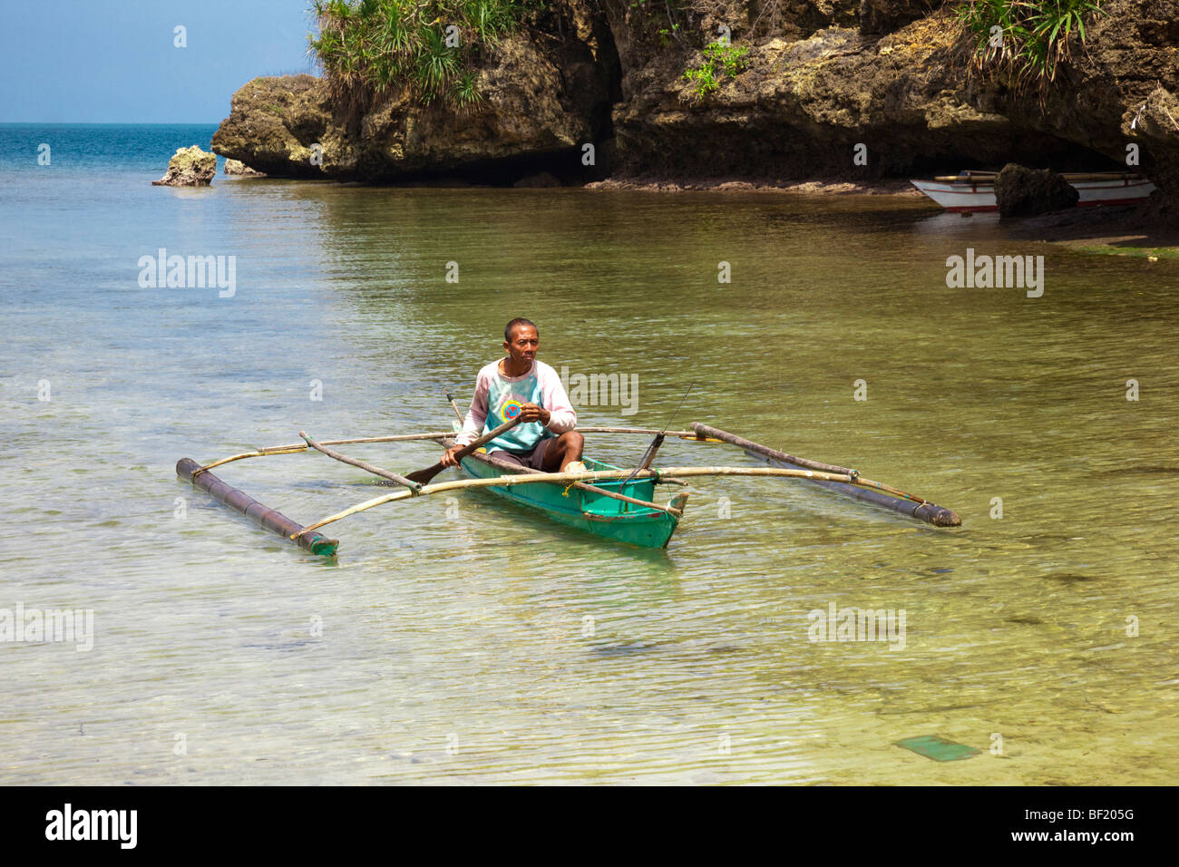 Filipino man paddling a traditional canoe (banca). Guimaras Island