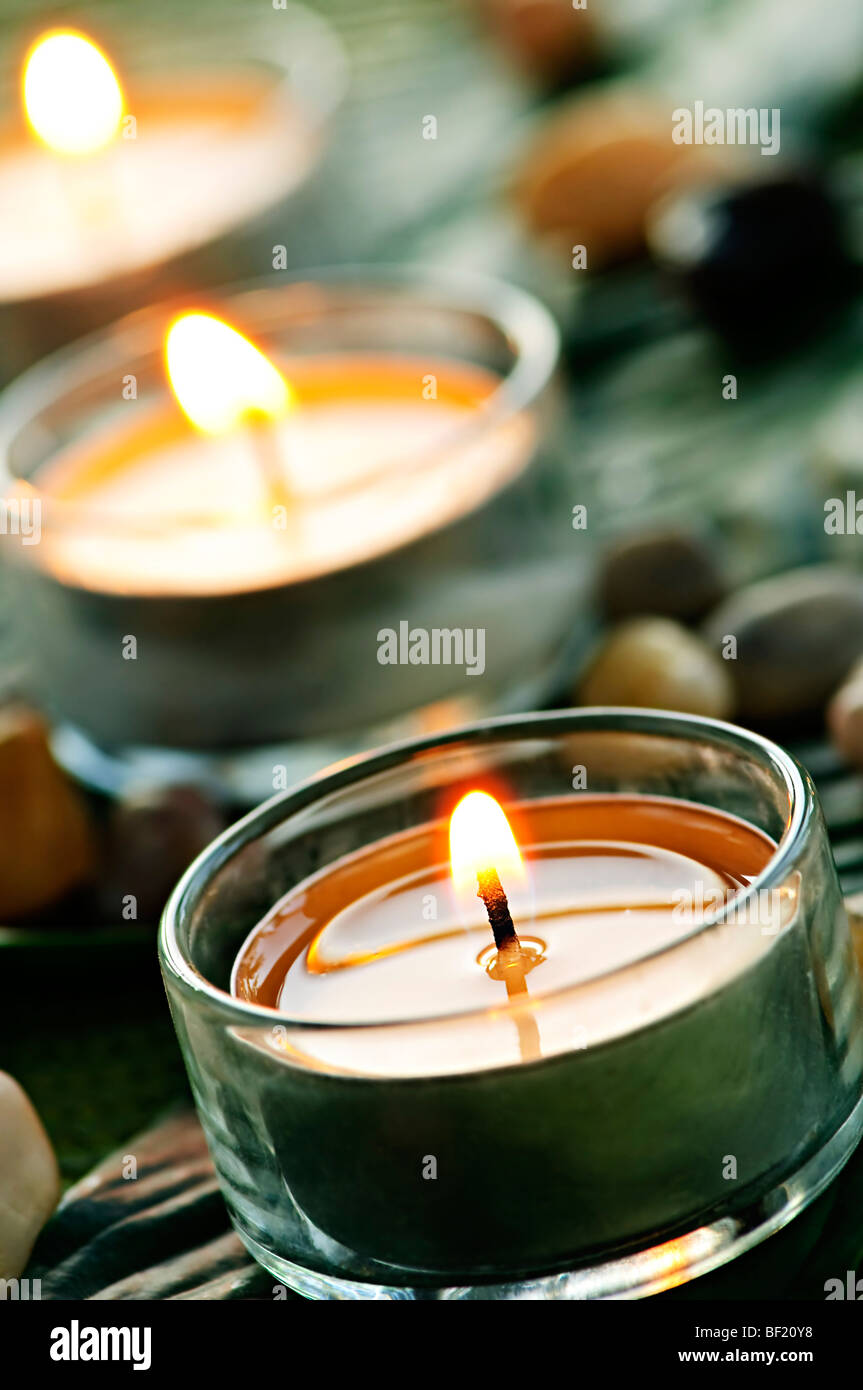 Burning candles in glass holders on green leaf Stock Photo