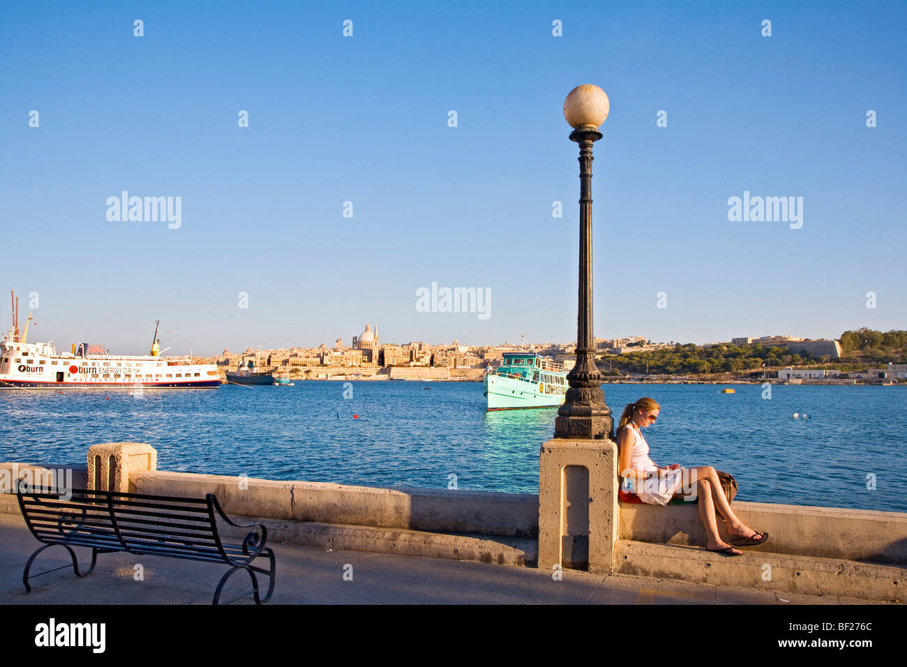 A woman sitting at the promenade of Sliema with view at Valletta, Malta, Europe Stock Photo